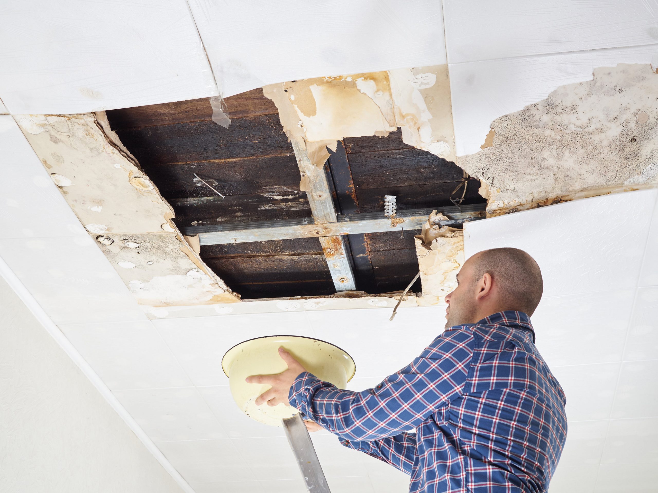 Man Collecting Water In basin From Ceiling