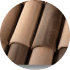 A close-up image of overlapping brown and tan bamboo rods arranged in a vertical pattern. The bamboo rods appear smooth with subtle variations in color and texture, creating a natural and organic look.